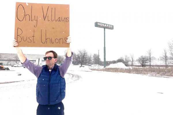 Tom protesting union busting by Menards, with a sign which states "Only Villains bust unions"